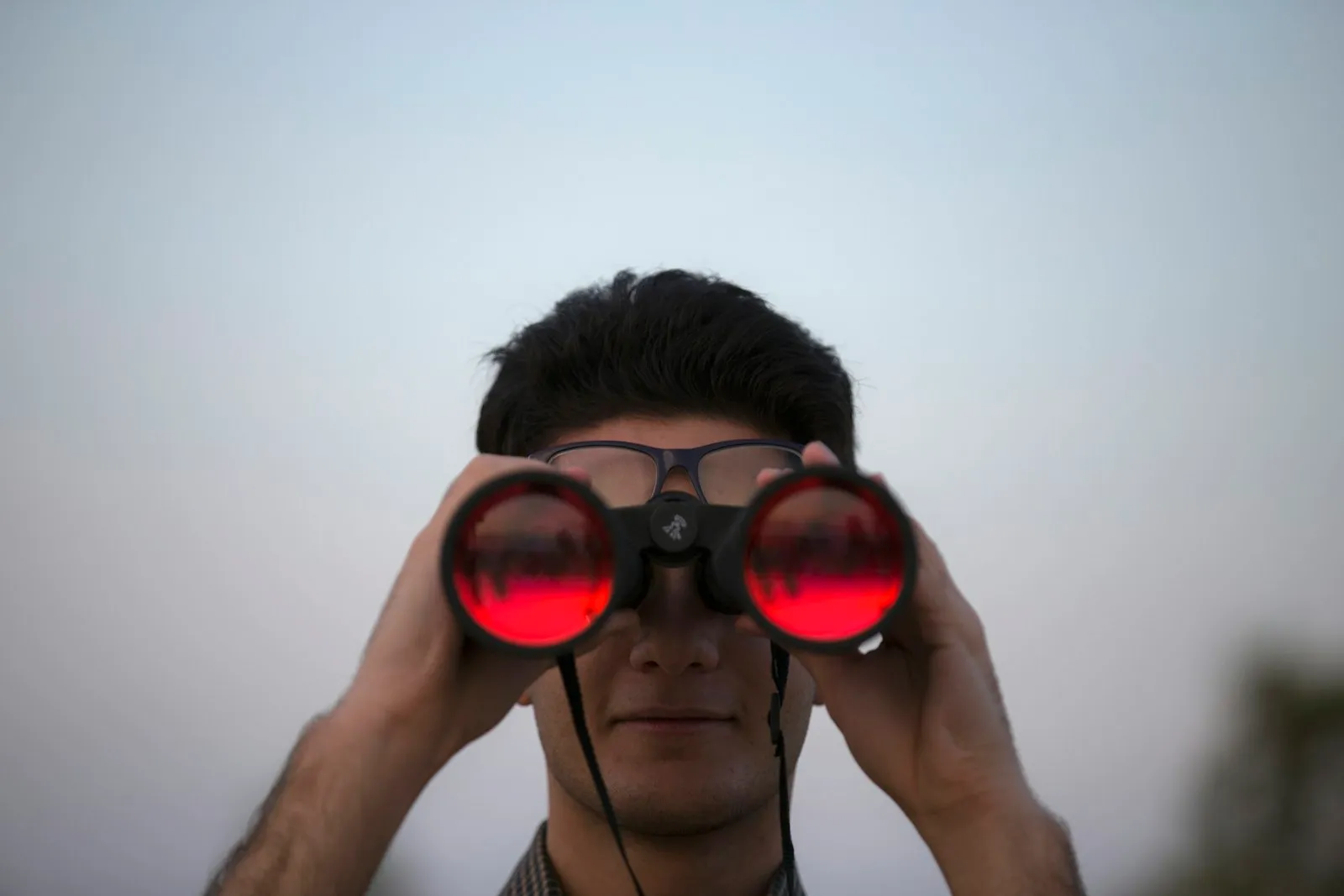 Person with binoculars looking into the distance — a classic long-range observation setup